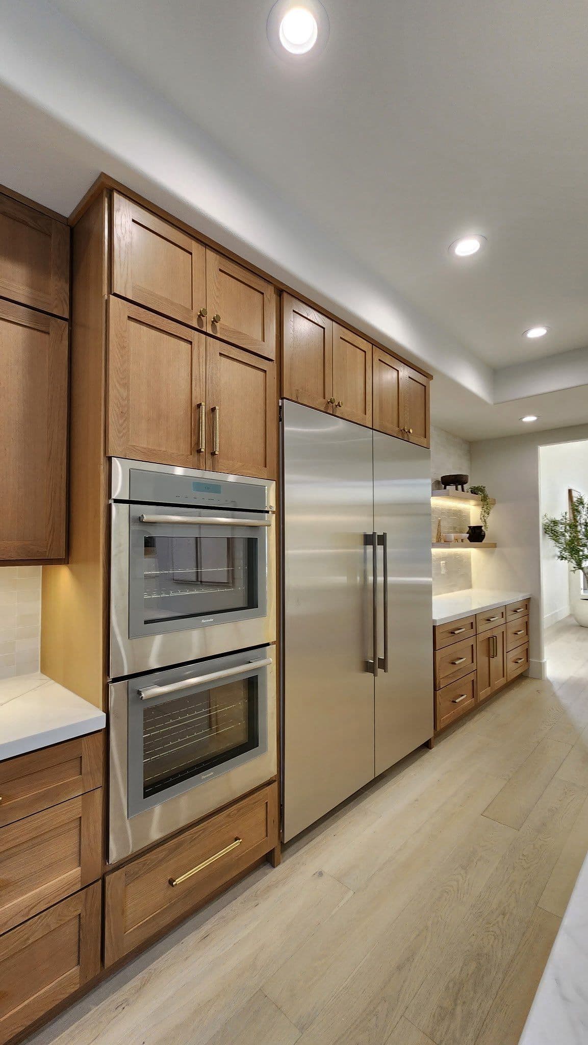 A kitchen with brown cabinets, stainless steel appliances, and large double-door fridge.